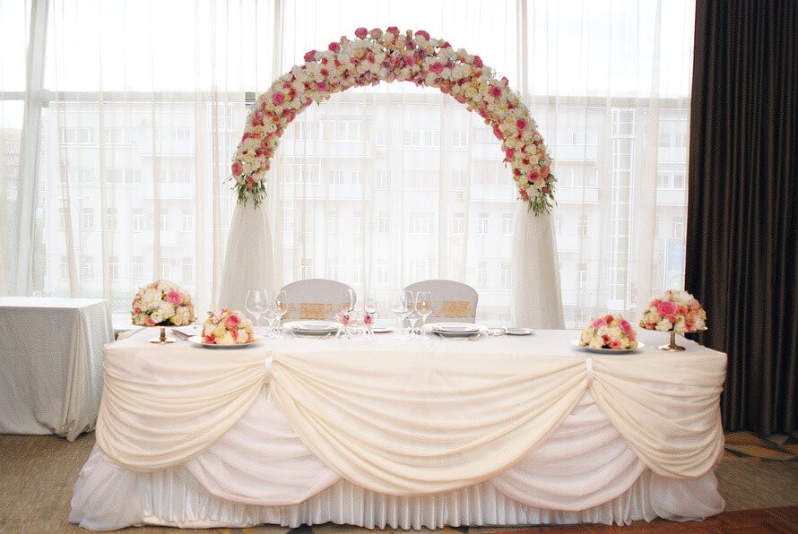 украшение свадебного стола аркой из цветов и тканями