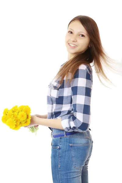 Девушка с букетом желтых полевых цветов. девушка в джинсах и клетчатой рубашке, держа букет одуванчиков — стоковое фото