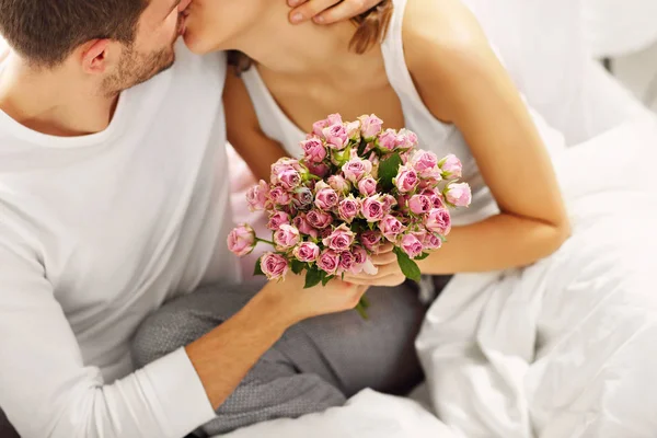 Человек, давая цветы к женщине в постели — стоковое фото