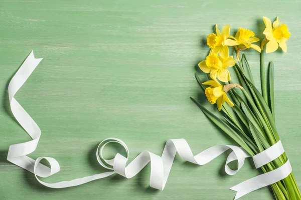 View Bouquet Daffodils Wrapped White Ribbon Green Background — стоковое фото