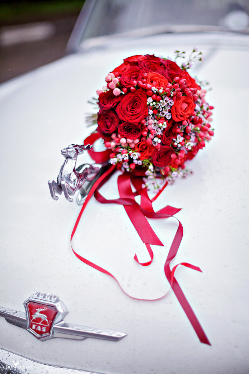 Классический красный букет невесты из роз с розовыми ягодами гиперикума и шамелациумом