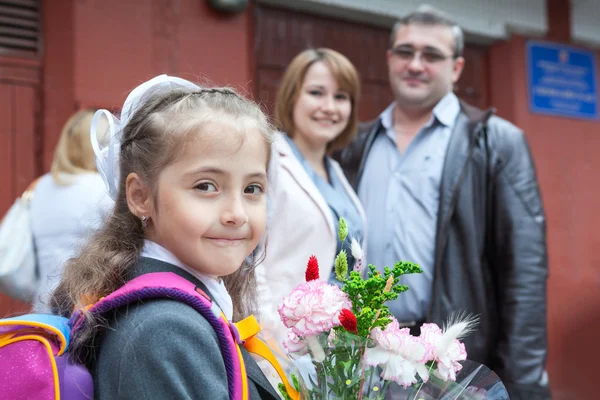 Маленькая школьница с ее родителями в школе — стоковое фото
