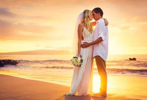 Жених и невеста, поцелуи на закате солнца на красивом тропическом пляже Стоковое Фото