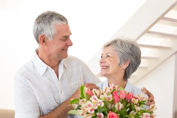 Пожилые супружеские пары, улыбаются друг другу, держа букет цветов Стоковое Фото