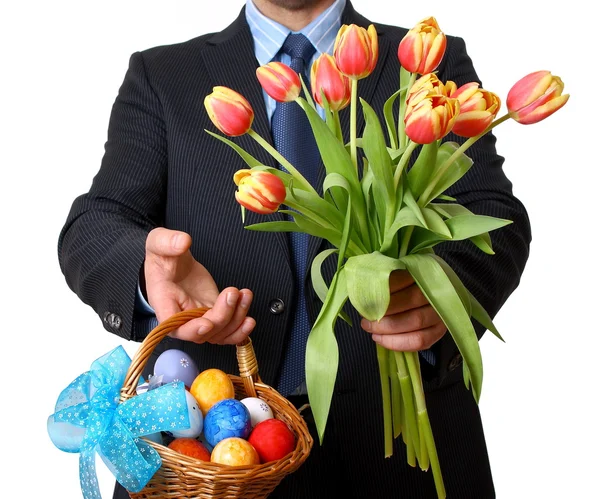 Человек в костюме и галстуке дает тюльпаны и Пасхальная корзина — стоковое фото