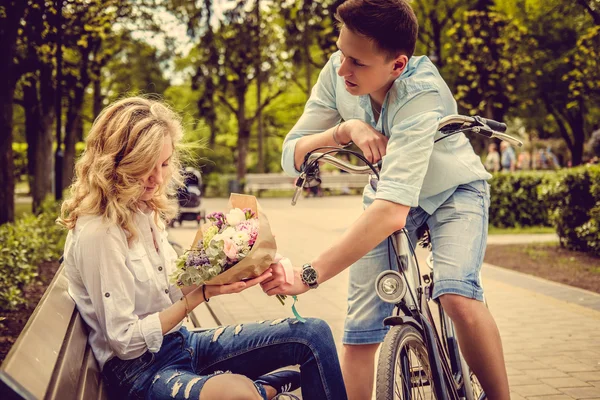 Мужчина на велосипеде дает цветы с его подругой — стоковое фото