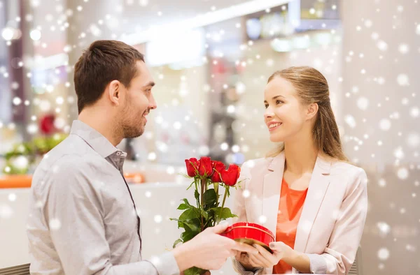 Счастливая пара с подарком и цветами в торговом центре — стоковое фото