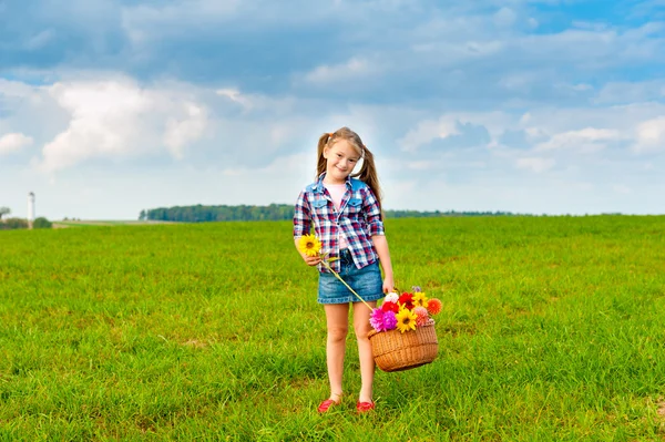 Открытый портрет очаровательны маленькая девочка, играя с цветами в поле в сельской местности на хороший солнечный день — стоковое фото