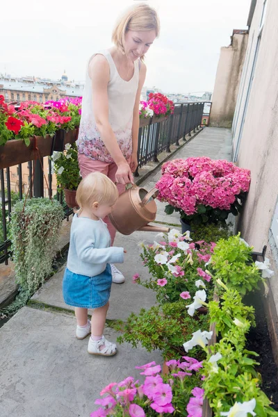 Мать с дочерью полива цветы на балконе — стоковое фото