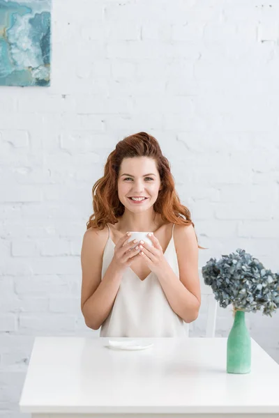 Счастливый Молодая Женщина Чашечкой Кофе Перед Стеной Белого Кирпича Глядя — стоковое фото