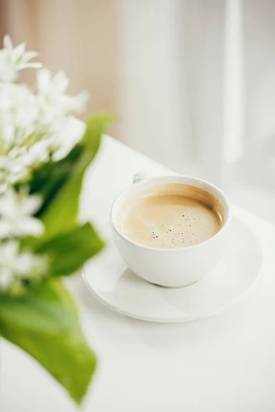 Чашка кофе с букетом цветов на столе — стоковое фото