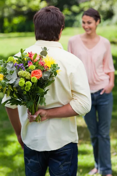 Человек собирается удивить его друг с букетом цветов Стоковая Картинка